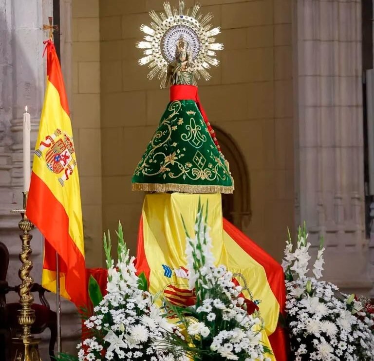 Imagen de la Virgen del Pilar con manto verde y emblema de la Guardia Civil junto a la bandera de España